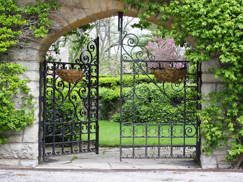 A partially open gate leading into a garden